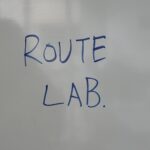 「ROUTE LAB.」と書かれたホワイトボードや黒板の文字、または授業中に使われたワークシート的なもの。スクール内の雰囲気が伝わるもの