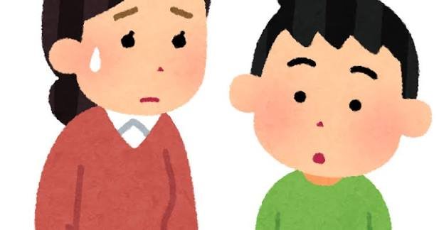 仕事のデスクに座りながら、スマホを見て少し心配そうな表情をしている保護者。職場にいながら子どものことを気にしている雰囲気