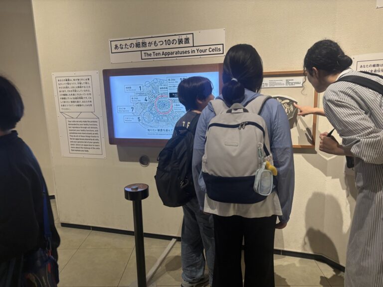 スタッフとお子さんが並んでプログラミングや学習に取り組んでいる様子。横から撮った自然な雰囲気で、顔が映りすぎない構図