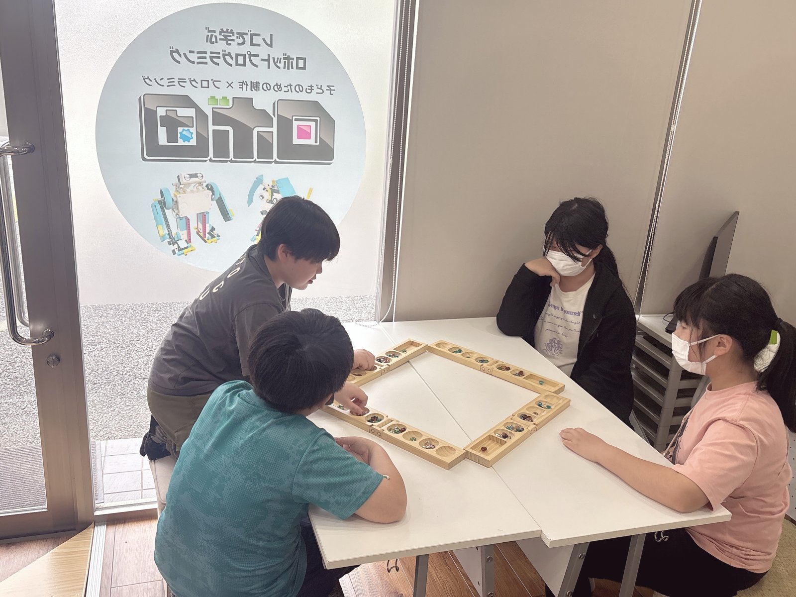 サムネイル|明るい窓のある教室で、子どもがスタッフと穏やかに話しているシーン。温かみのある自然光。