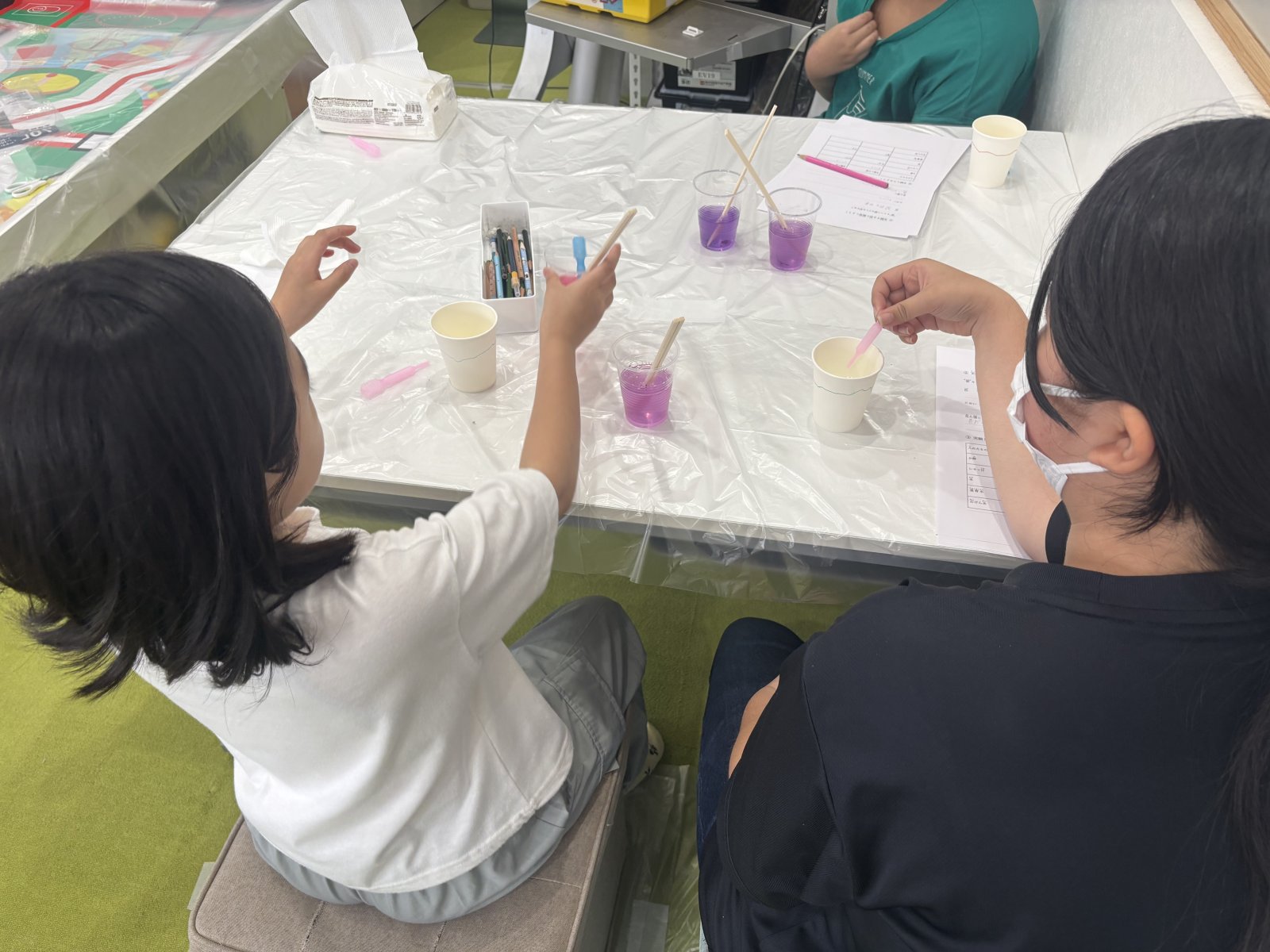 生徒がスポイトで液を加えながら、コップの色が変化していくのを確認している場面。真剣な表情とわくわくした表情が入り混じっている様子