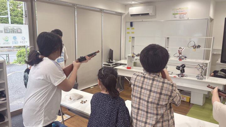 スタッフと子どもが横に並んで座り、ホワイトボードや紙を前に何かを一緒に考えている様子。対話のある温かいシーン