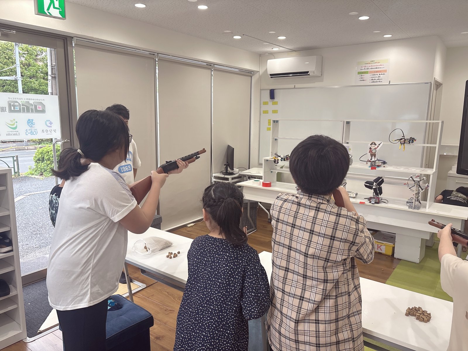 スタッフと子どもが横に並んで座り、ホワイトボードや紙を前に何かを一緒に考えている様子。対話のある温かいシーン