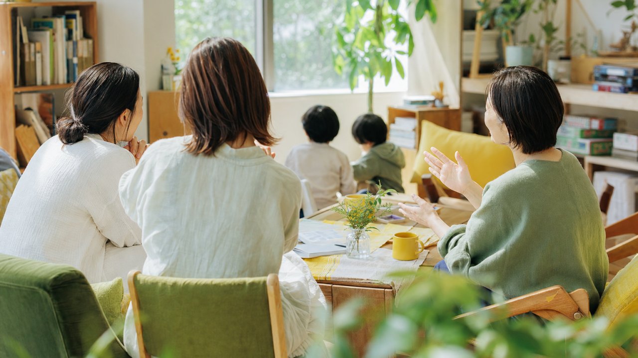 保護者同士がカフェや部屋で向き合って話している様子。リラックスした雰囲気で、「つながれる場所」のイメージ