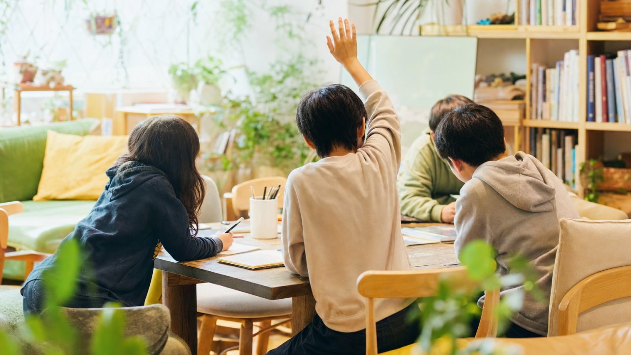フリースクールの室内。子どもがスタッフと穏やかに話しているか、一人で本を読んでいるなど、静かで安心感のある雰囲気のもの