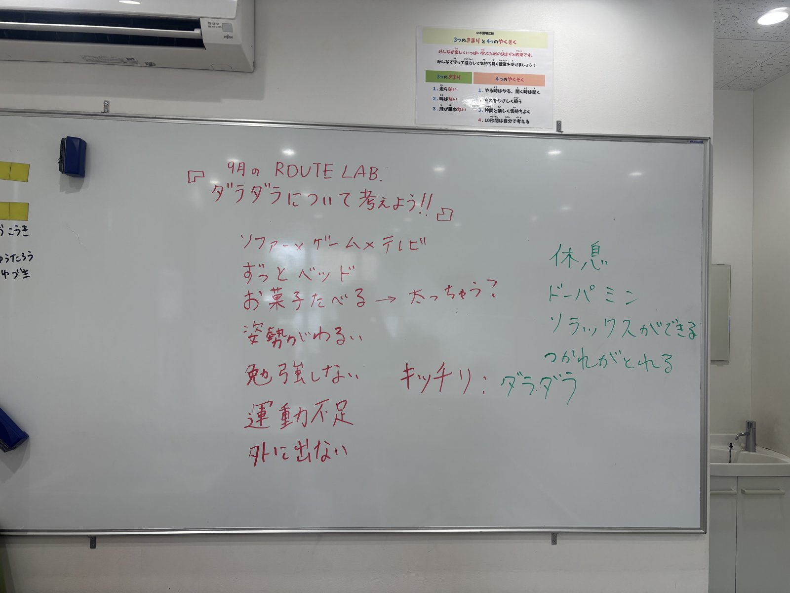 子どもたちがホワイトボードの前で話し合っているようす。笑顔や考え込む表情が混在している、温かい雰囲気の写真