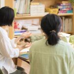 スタッフが保護者と穏やかに話している様子。テーブルを挟んで、安心感のある雰囲気で対話しているシーン