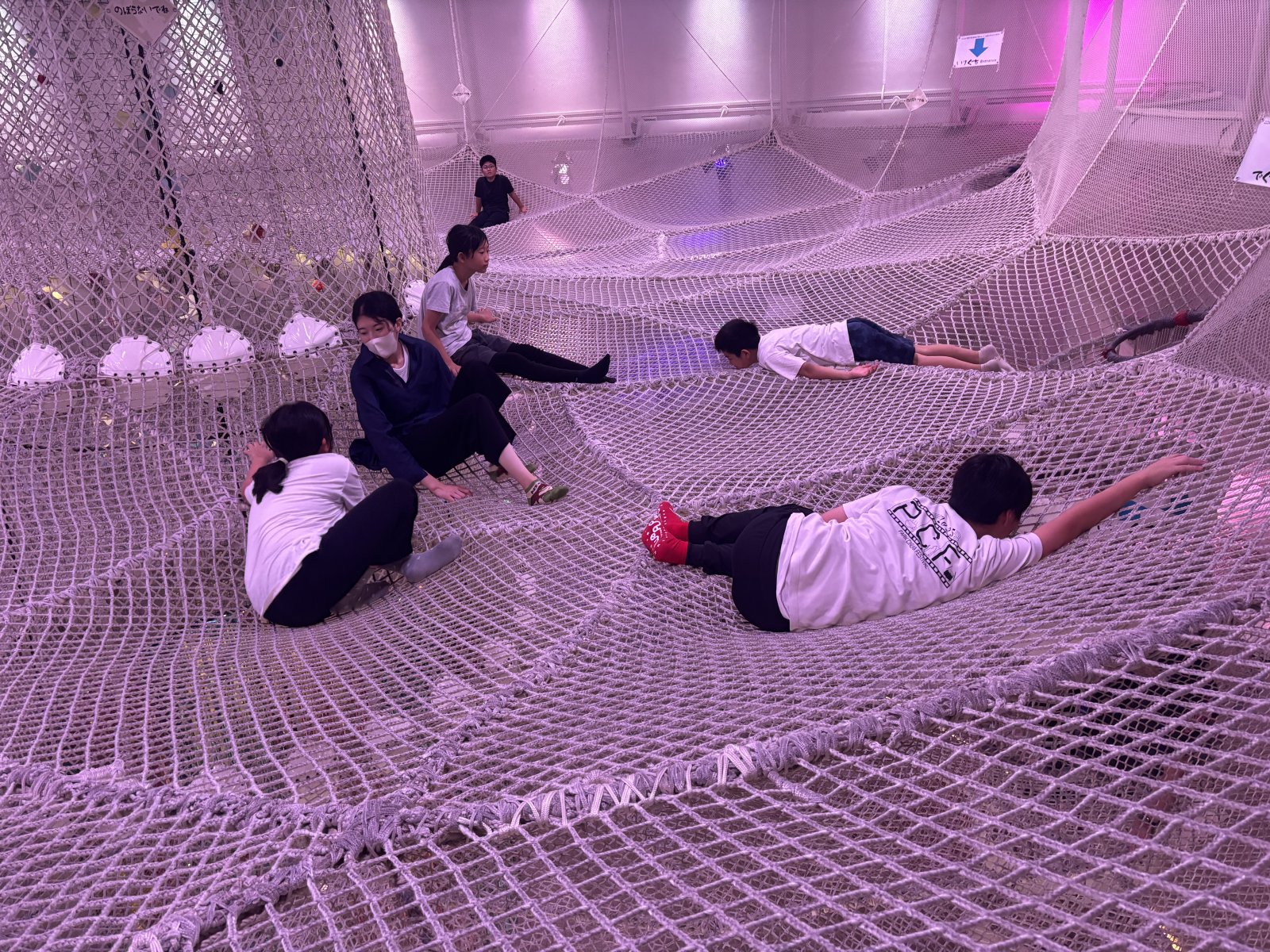 スペースあすれちっくのネット遊具を元気よく登っている子どもたちの後ろ姿