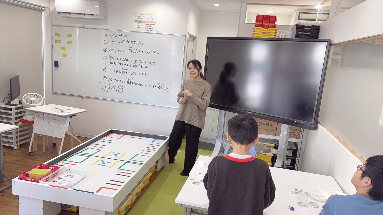 子どもとスタッフが穏やかに向き合って話している様子。フリースクールの温かい室内、笑顔が見える場面
