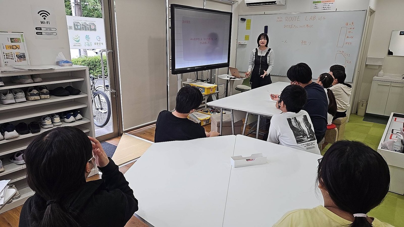 サムネイル|子どもたちが輪になって話し合っている様子。明るく温かみのある雰囲気で、ホワイトボードや模造紙が見えるとベスト