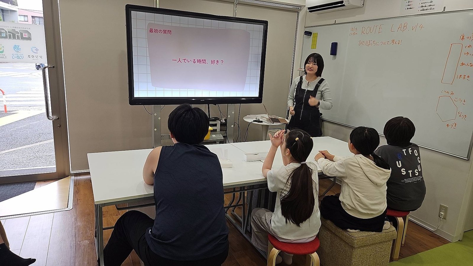 子どもたちが少人数でテーブルを囲んで話し合っている様子。スタッフが横に座って一緒に考えている場面だとベスト