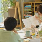 スタッフが手書きのメモや記録ノートを広げながら丁寧に話しているイメージ。面談の雰囲気が伝わる写真