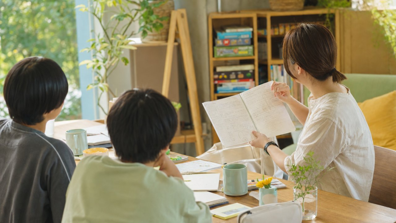 スタッフが手書きのメモや記録ノートを広げながら丁寧に話しているイメージ。面談の雰囲気が伝わる写真